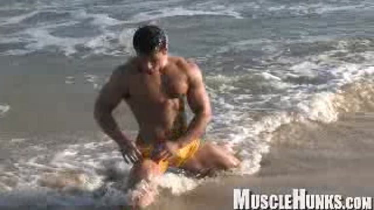 Muscular Benjamin flexes on the beach