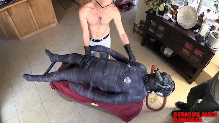 the rubber gimp wears full bondage suit