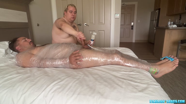 chubby man mummified in plastic for tickling session