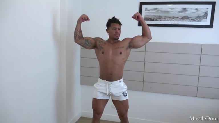 bodybuilder in white shorts flexes his big biceps