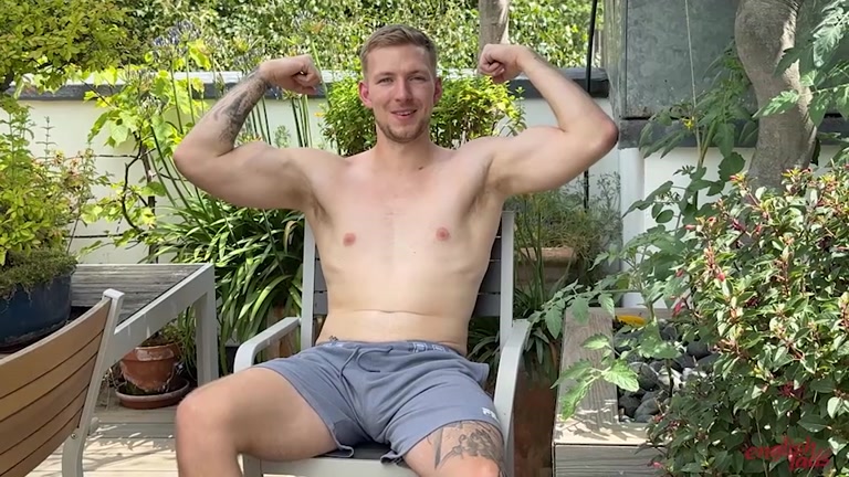 Handsome Young Man in Shorts Flexes Biceps on Rooftop Garden 